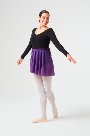 Eine junge Frau im Ballettkostüm posiert mit ausgestreckten Armen und trägt einen schwarzen Ballettanzug