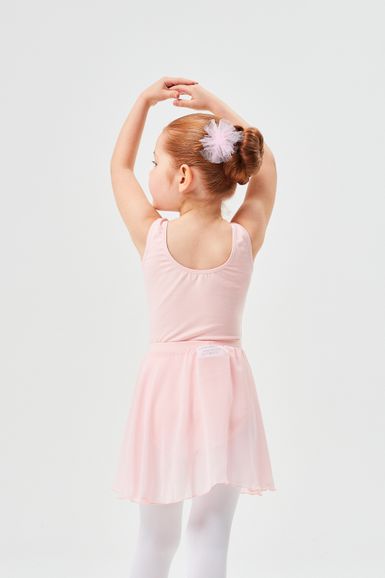 Ein junges Mädchen in einem rosa Ballett-Outfit steht mit erhobenen Armen