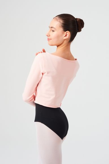 Eine junge Ballerina in einem rosa Oberteil und einem schwarzen Trikot steht in einer Tanzpose.