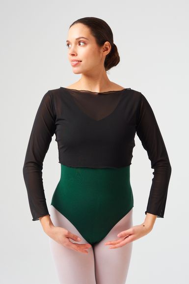 Eine Frau in einem schwarzen Langarm-Trikot posiert in Ballettposition und blickt zur Seite.