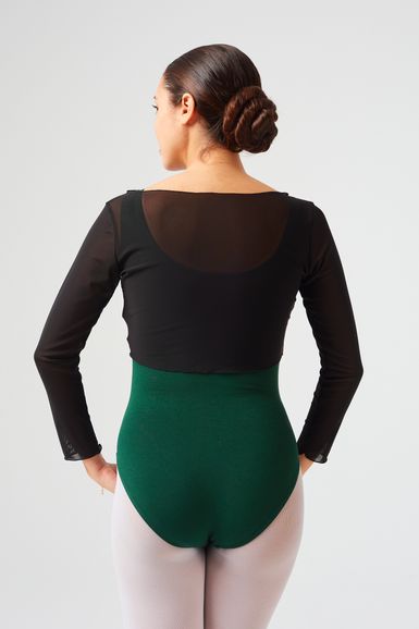 Eine Frau mit dunklem Haar zu einem Dutt trägt einen schwarzen Langarmbody mit grünem Unterteil und blickt von der Kamera weg.