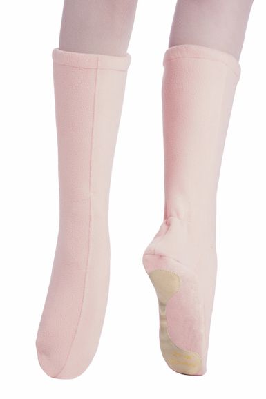 Ein Paar Füße in hellrosa Fleece-Hausschuhen mit flachen Sohlen