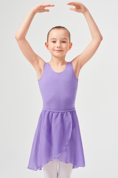 Ein junges Mädchen in einem lavendelfarbenen Ballett-Outfit posiert mit erhobenen Armen in einer Ballettposition.