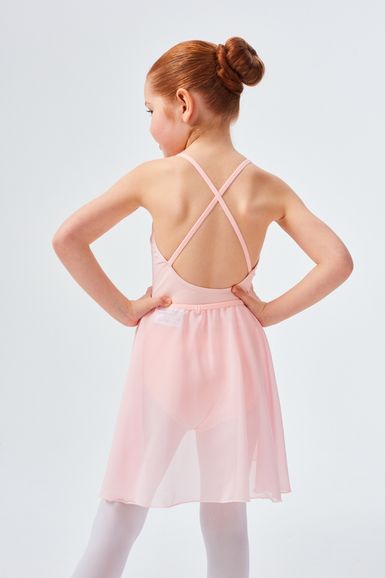 Ein junges Mädchen in einem rosa Ballettkleid steht mit den Händen in den Hüften und blickt von der Kamera weg.