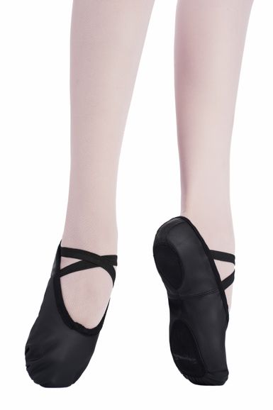 Zwei Füße in hellen Strumpfhosen und schwarzen Lederballettschuhen mit überkreuzten elastischen Riemen