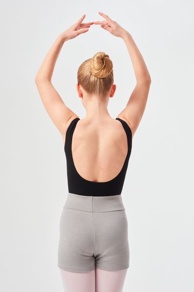 Eine Balletttänzerin mit Dutt posiert mit über den Kopf erhobenen Armen