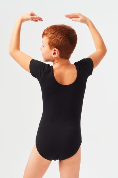 Kind mit kurzen roten Haaren posiert in einem schwarzen Ballett Trikot.