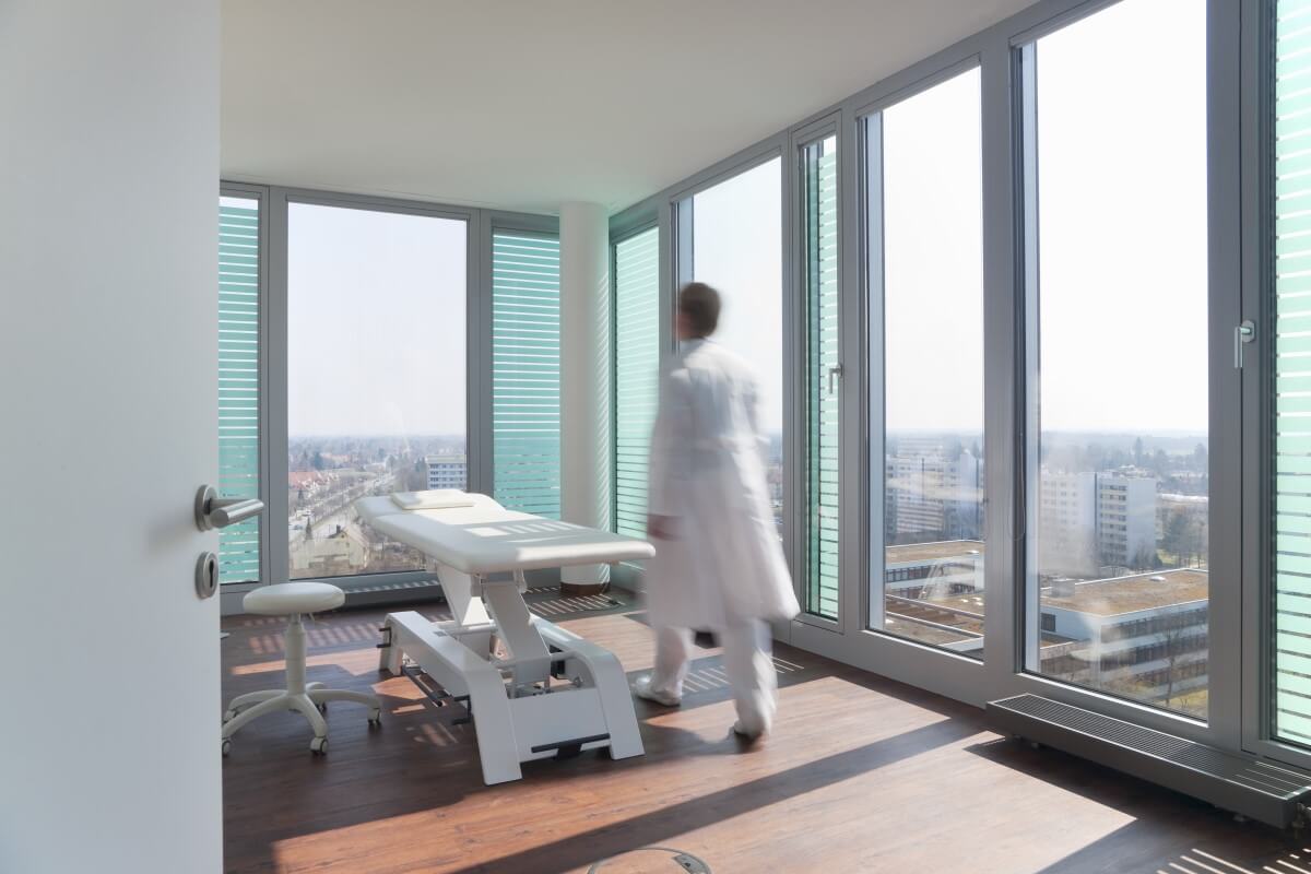 Behandlungsliege in der Physio Ein Arzt ist in einem Behandlungsraum und hat eine Behandlungsliege mit einer Liegenabdeckung versehen