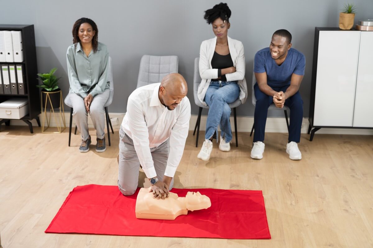 Training mit einer CPR Puppe von SANISMART Eine Gruppe an Personen nimmt an einem erste Hilfe Training mit einer CPR Puppe teil