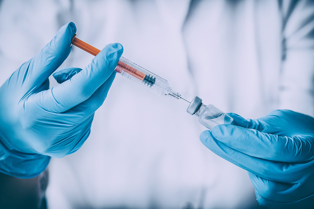 Einmalhandschuhe in der Medizin Behandschuhte Hände ziehen eine Spritze auf – Einmalhandschuhe schützen im Medizinbereich vor Keimübertragung