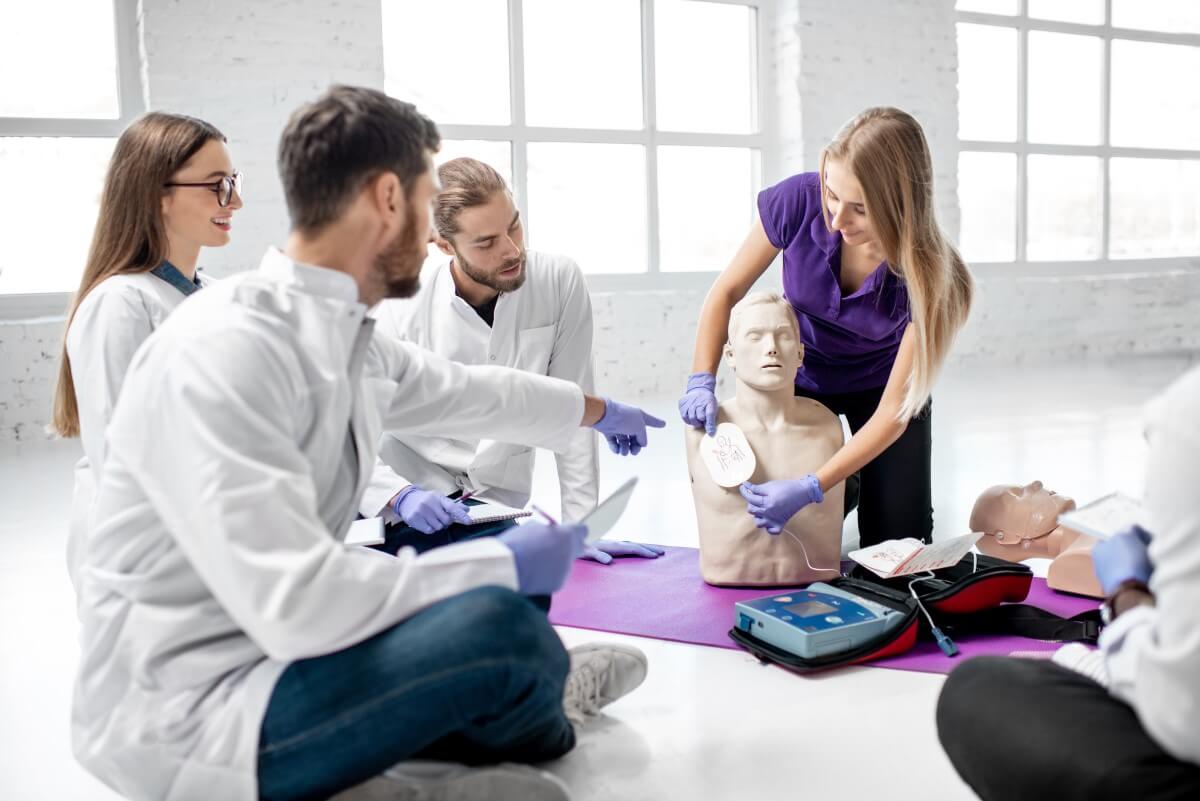 Für die Nutzung von einem AED bedarf es einer Einweisung Ein Mann weist Mitarbeiter in die Nutzung von einem AED ein