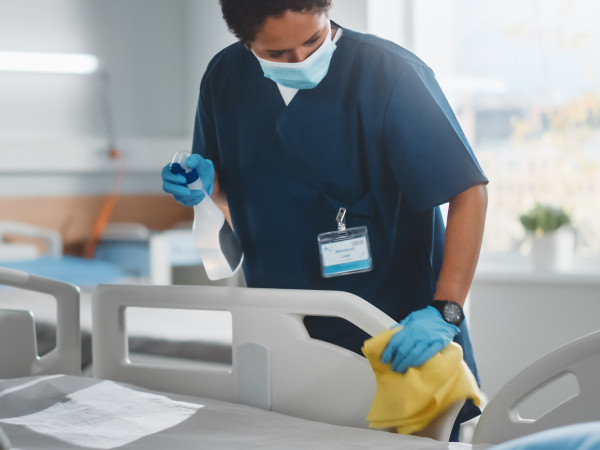 Hygienebedarf Eine Frau putz eine Krankenliege mit Hygienebedarf