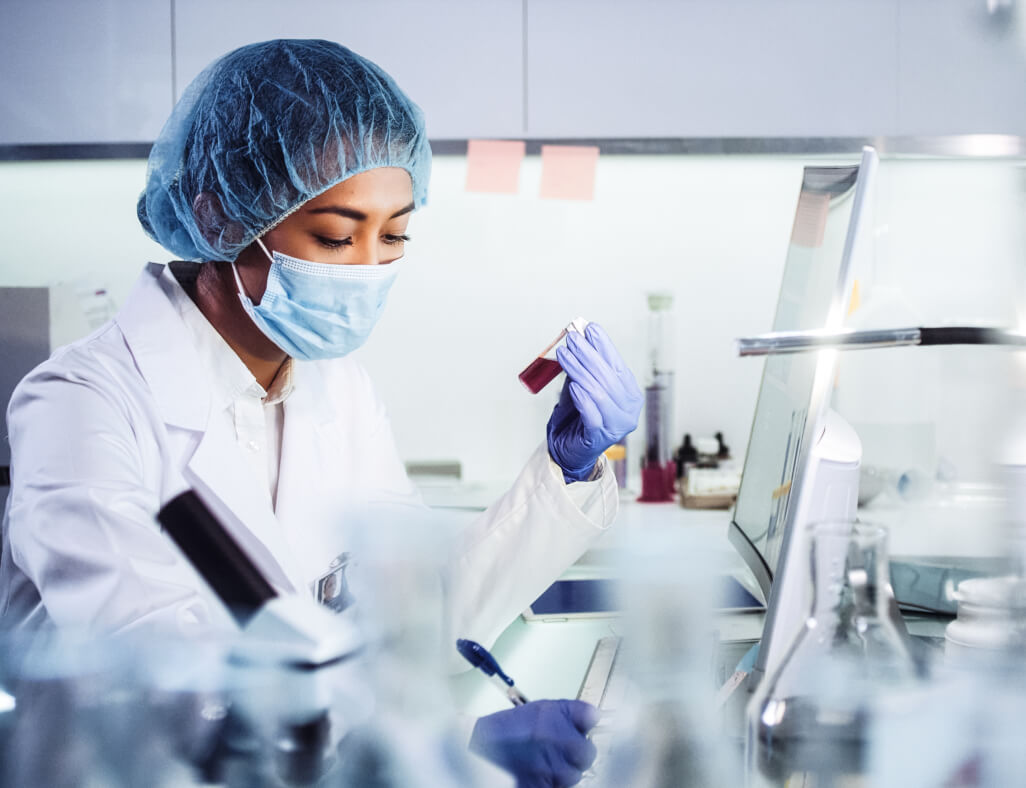 Medizinische Schutzkleidung im Labor Eine Laborantin untersucht Proben –¬ sie trägt medizinische Schutzkleidung
