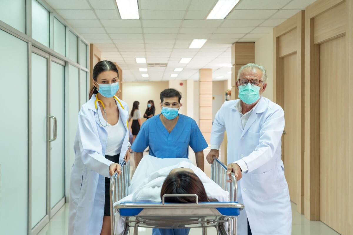 Patiendecke bei Operation Ein Mann wird von Ärzten in den Operationssaal geschoben – er ist mit einer Patientendecke bedeckt.