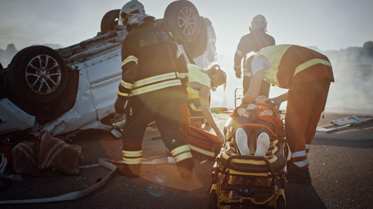 Rettungstücher für den Feuerwehreinsatz Feuerwehrmänner legen eine verletzte Person an einem Unfallort von einem Rettungstuch auf eine Rettungstrage.