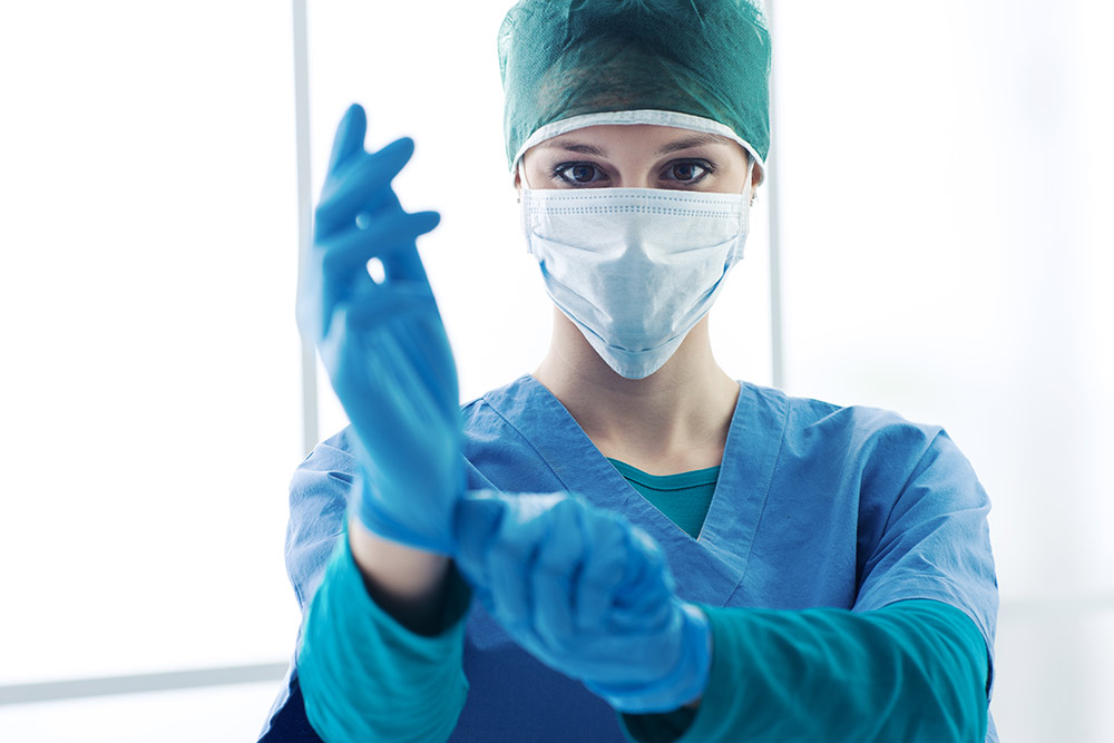 Untersuchungshandschuhe anziehen Eine Ärztin zieht vor der Behandlung Untersuchungshandschuhe an.
