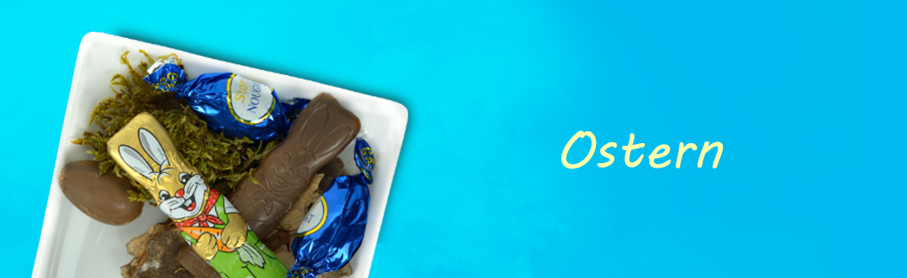 In einer Schale liegen Schokoladenhasen und Schokoeier, mit Heu als Deko