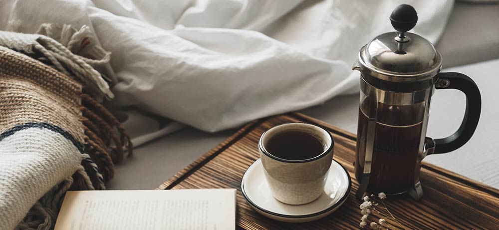 frischer Kaffee in einer French Press im Bett