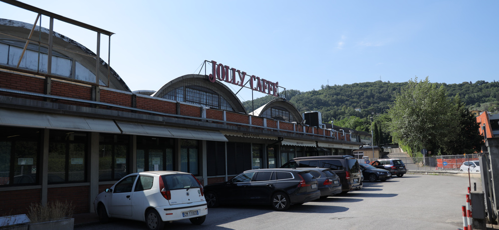 Gebäude der Rösterei Jolly Caffè bei Florenz mit rotem Dachschriftzug und Tonnendächern