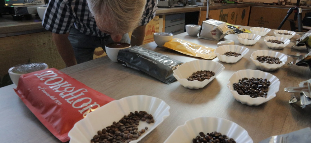 Cupping des gesamten Sortiments mit Michael Eckl — so schärfen wir Geschmacksprofile Walter Gefäll bei der Sortimentsverkostung mit Michael Eckl — Bohnen in Cupping-Schalen vor mehreren Espresso-Packungen zur Geschmacksprofil-Schärfung