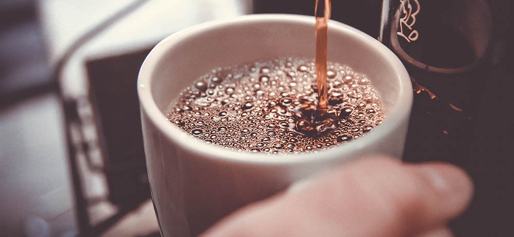  Von einer Kaffeemaschine rinnt Kaffee in eine Tasse 