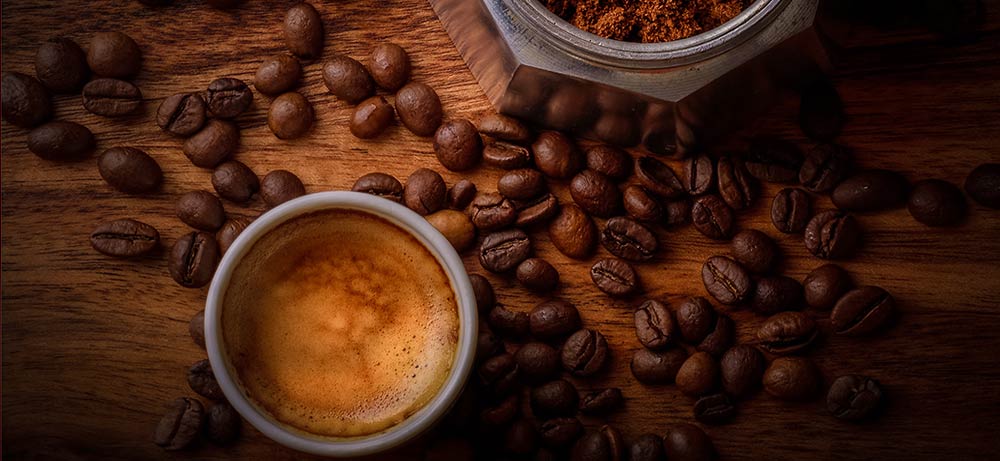 Kaffeesucht Tasse mit Kaffee, Unterteil einer Espressokanne und Kaffeebohnen auf Holztisch