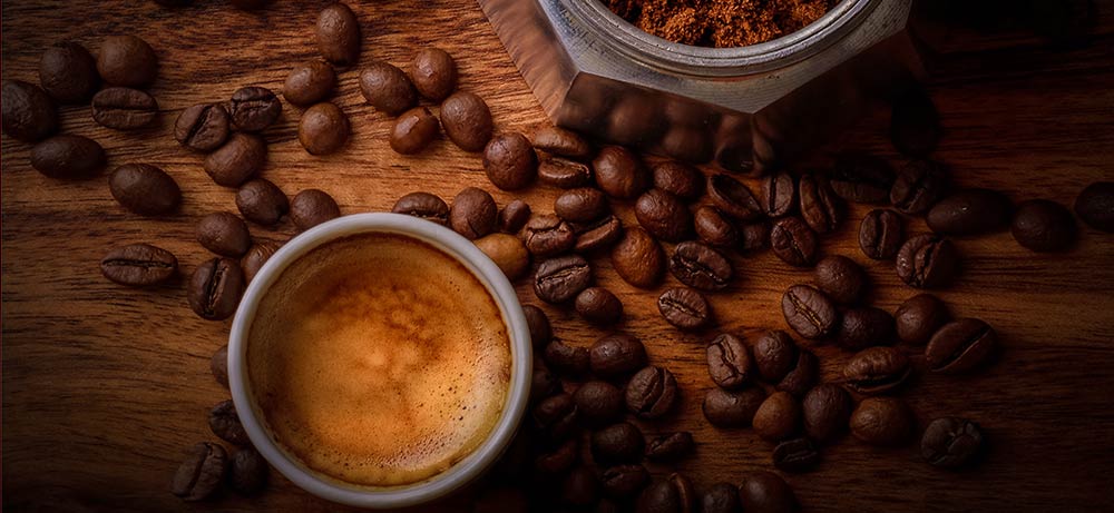  Tasse mit Kaffee, Unterteil einer Espressokanne und Kaffeebohnen auf Holztisch 