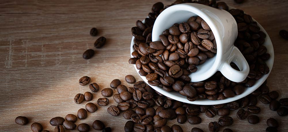 Koffeinfreie Bohnen weiße Tasse mit Kaffeebohnen von der Seite