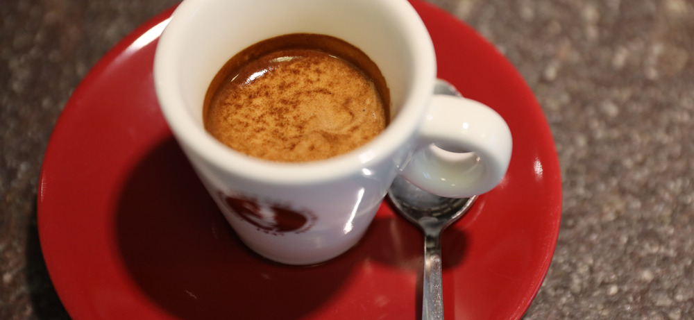 Ein Espresso aus dem Omkafe-Sortiment — mit voller, samtiger Crema Frischer Espresso in einer Omkafe-Tasse mit goldener Crema, serviert auf rotem Unterteller