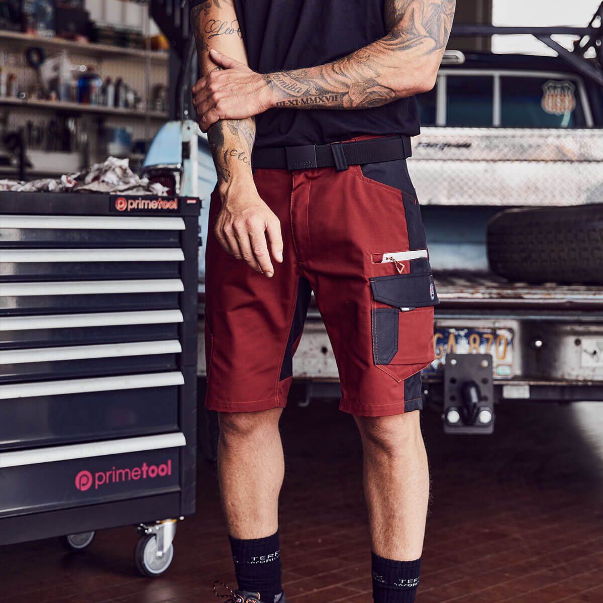 Beinbereich eines Mannes mit einer Arbeitsshorts von Terrax Workwear im Werkstattbereich