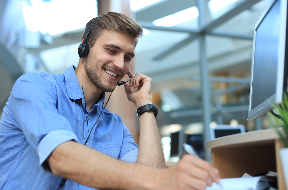 Junger Mann mit Headset am Computer