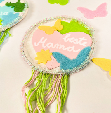 Button, geschmückt mit Filzfiguren, Wolle und der Aufschrift "Beste Mama"
