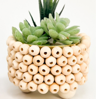 Nahaufnahme eines mit Holzperlen geschmückter Blumentopf.