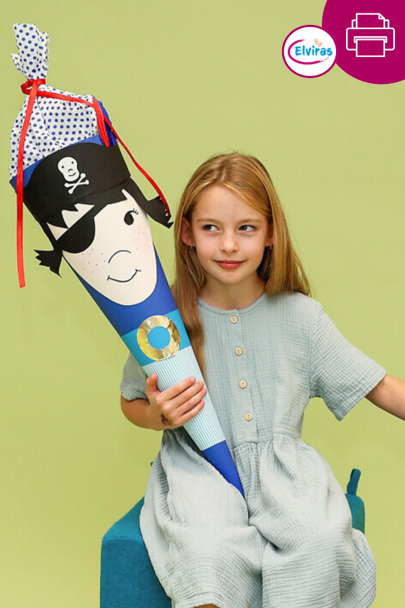 Mädchen guckt frech. Sie hat eine Piratin-Schultüte in der Hand. Diese ist aus euinem blauen Rohling und hat ein großes Gesicht aus Fotokarton.