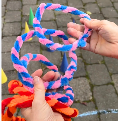 Zwei Hände halten mehrere Ringe , die aus ineinander gedrehte Pfeifenputzer bestehen.