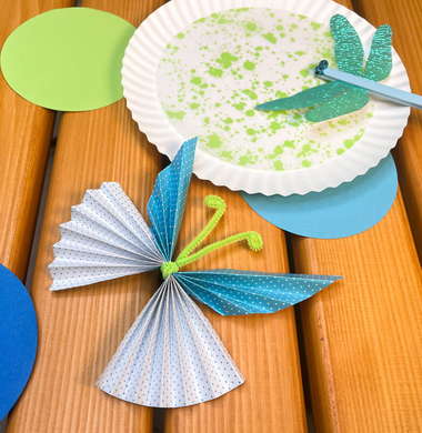 Sommerliche gebastelte Deko: Ein Scgmetterling aus bunten Papier und einem Pfeifenputzer. Eine Libelle aus einem Holzstab und Glitzerpapierflügel.