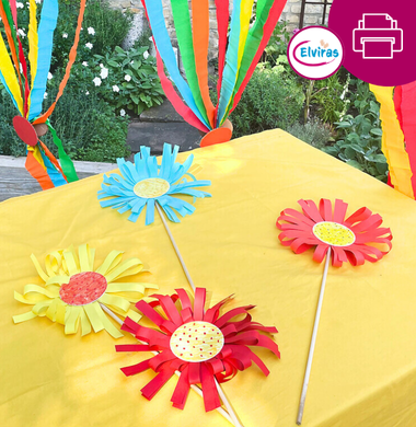 Sommerlich dekorierter Tisch: Gelbe Tischdecke und große gebastelte Blumen. Im Hintergrund sieht man buntes Krepppapier als Girlande.