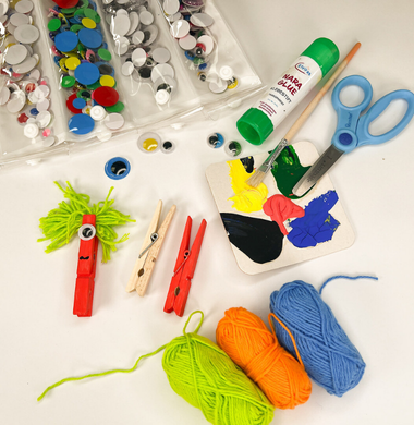Gebasteltes Wäscheklammermonster und die verwendeten Materialien daneben: Wäscheklammern, Wolle, Farbe, Wackelaugen, Schere und Kleber.