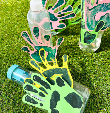 Leere Plastikflaschen, die dekoriert sind mit auf Tonpapier  gedruckten Handabdrücken.