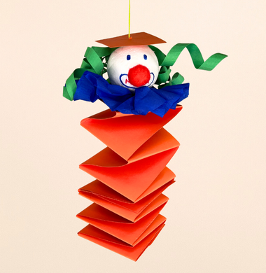 Ein Hexenleiterclown. Die Papier-Hexenleiter wurde mit einem Styropor-Ball, Krepppapier, einem Pompon und Haaren aus Tonpapier geschmückt.