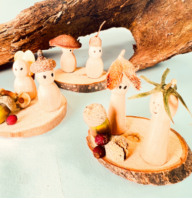 Kleine Holzfiguren, die mit Naturmaterialien dekoriert sind.