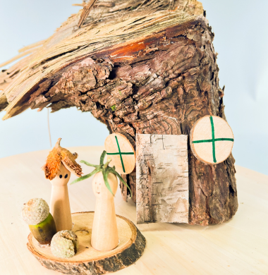 Kleine Holzfiguren, die mit Naturmaterialien dekoriert sind.