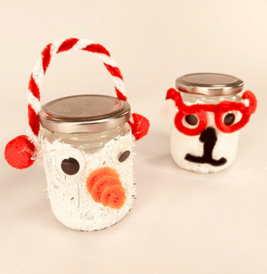 Zwei Bläser, die weiß angemalt sind und mit Chenille, Pompons und Wackelaugen geschmückz sind. Das eine Glas stellt einen Schneemann dar, das andere einen Eisbären.