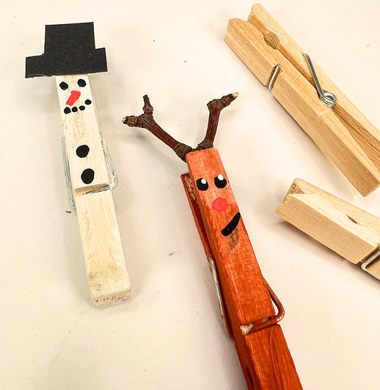 Eine Schneemann- und eine Rentierfigur aus je einem bemalten Wäscheklammer.