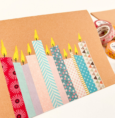 Weihnachtskarte aus braunem Tonpapier. Geschmückt mit Washi-Tape-Streifen, die zu Kerzen dekoriert wurden.