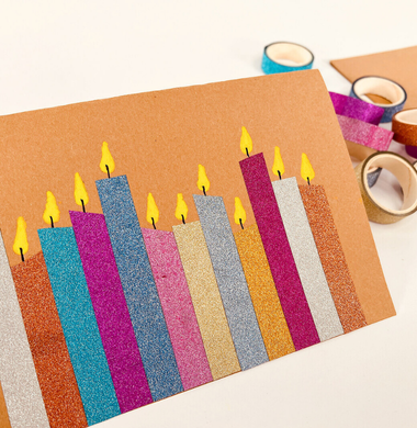 Weihnachtskarte aus braunem Tonpapier. Geschmückt mit Washi-Tape-Streifen, die zu Kerzen dekoriert wurden.