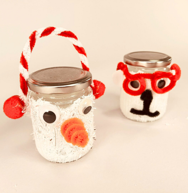 Zwei Marmeladen-Gläser, die weiß angemalt sind und mit Chenille, Pompons und Wackelaugen geschmückz sind. Das eine Glas stellt einen Schneemann dar, das andere einen Eisbären