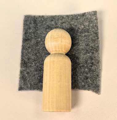Eine Holzfigur, die in Bastelfilz gekleidet wird.