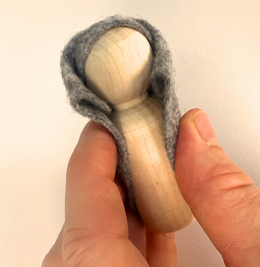 Eine Holzfigur, die in Bastelfilz gekleidet wird.