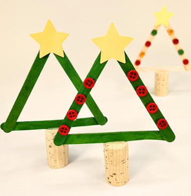 Ein Tannenbaum aus drei bemalten Holzstäbchen und einem Stamm aus einem Bastelkorken.